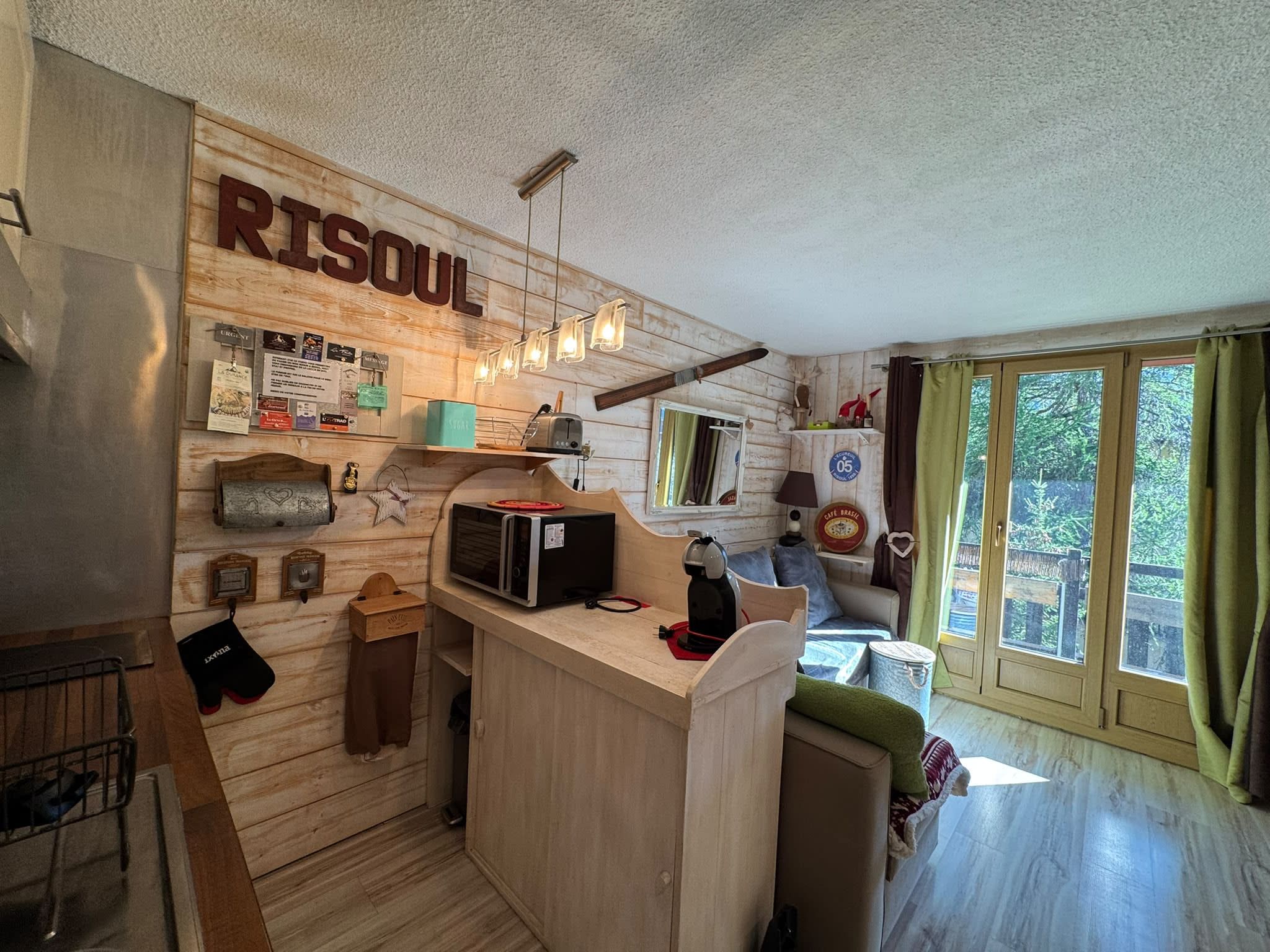 A rustic kitchen with wooden walls, a wooden counter, and a view of the outdoors through a window.