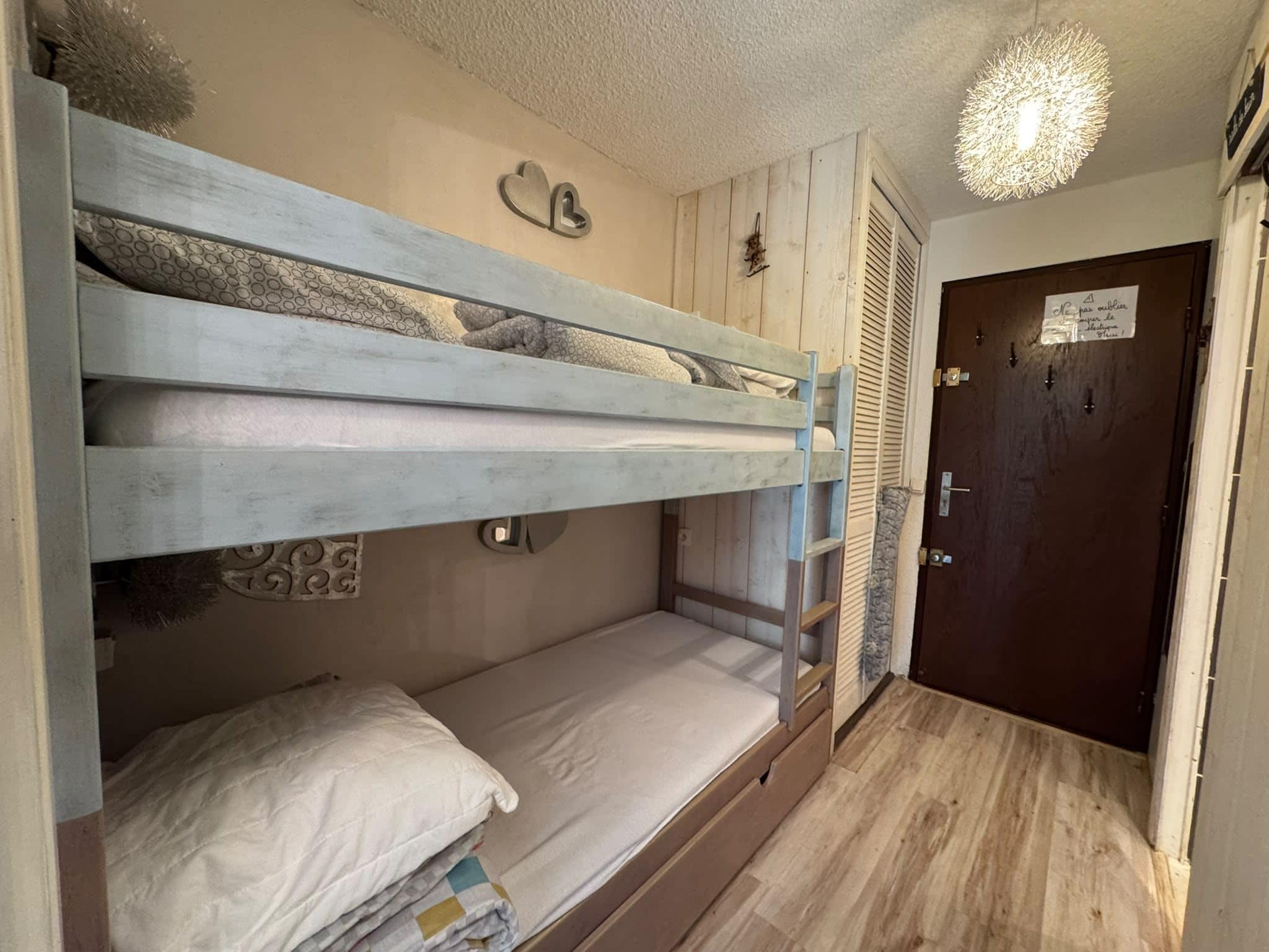A bunk bed room with a door and a light fixture.