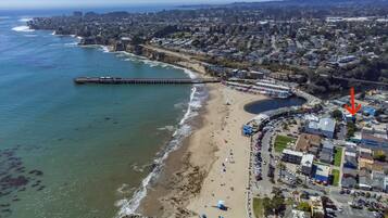 Vue aérienne d’une ville côtière avec une plage, une jetée et des immeubles résidentiels.