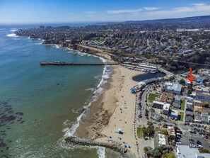 An aerial view of a coastal town with a beach, a pier, and residential buildings.