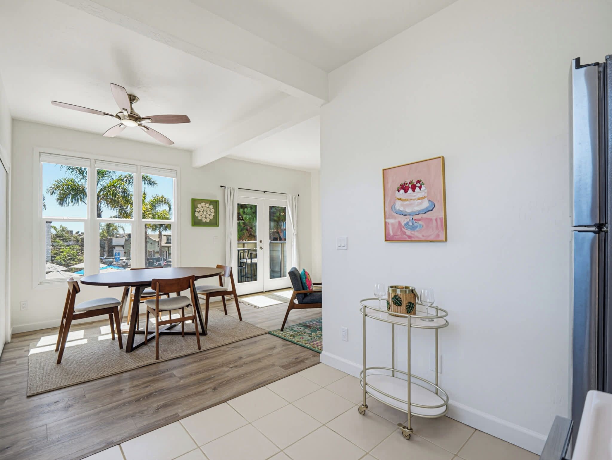 A spacious kitchen with a dining area, large windows, and a ceiling fan.