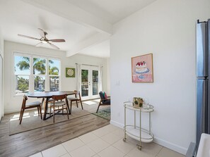 A spacious kitchen with a dining area, large windows, and a ceiling fan.