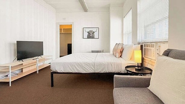Una habitación de hotel con cama, sofá, televisor y radiador.