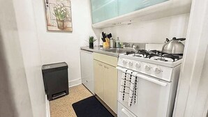 Una cocina compacta con estufa a gas, un refrigerador pequeño y un solo gabinete.