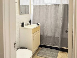 A small bathroom with a toilet, sink, and mirror. - Trendy Gold Coast Studio Close to Downtown (Chicago)