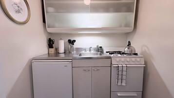 Une petite cuisine équipée d’un réfrigérateur, d’une cuisinière, d’un évier et d’un tableau encadré accroché au mur.