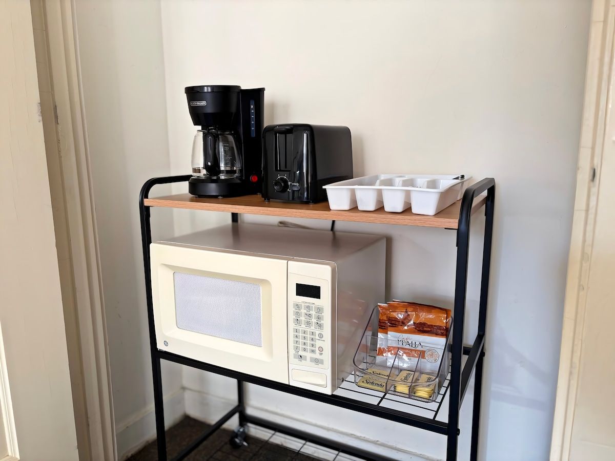 Un chariot de cuisine équipé d’un four à micro-ondes, d’un grille-pain, d’une machine à café et de boîtes de rangement.
