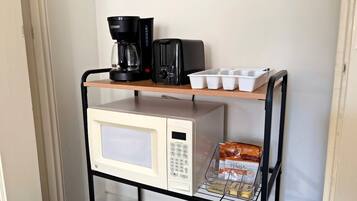 Un chariot de cuisine équipé d’un four à micro-ondes, d’un grille-pain, d’une machine à café et de boîtes de rangement.
