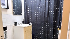 A compact bathroom with a toilet, sink, and cabinet. - Gold Coast Hideaway | Vintage & Inviting Studio (Chicago)