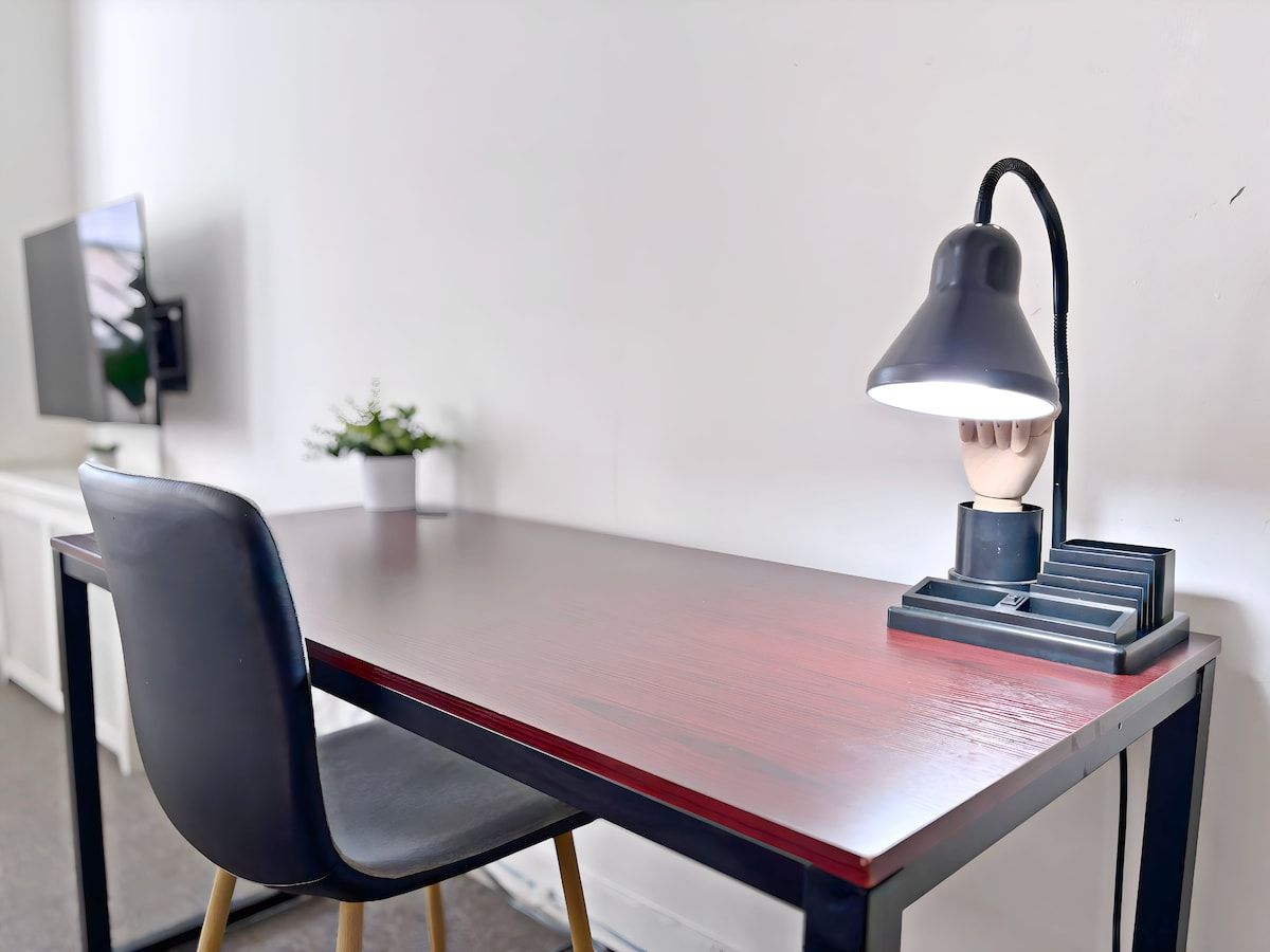 A desk with a lamp, a chair, and a small potted plant.