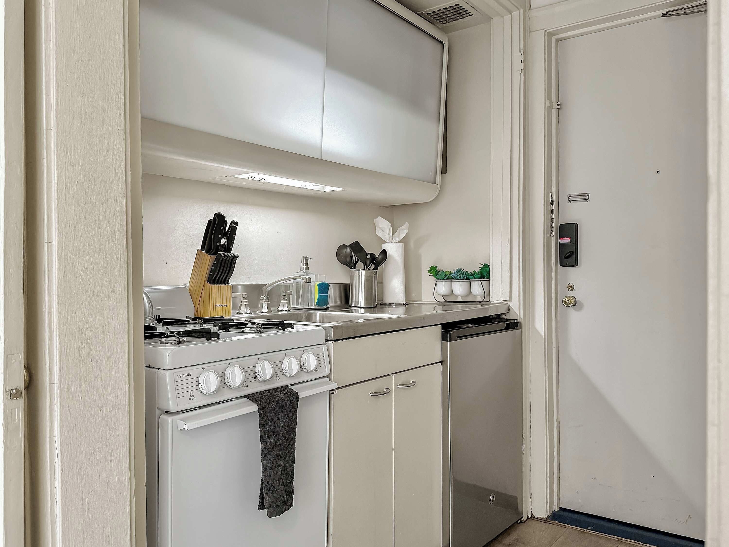 A compact kitchen with a stove, sink, and cabinets.