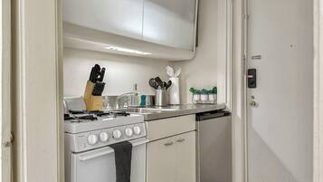A compact kitchen with a stove, sink, and cabinets.
