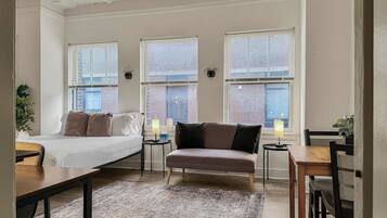 A modern bedroom with a bed, two side tables, a chair, and a dining table.