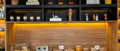 A breakfast bar with a variety of pastries, a coffee machine, and a display of jars.