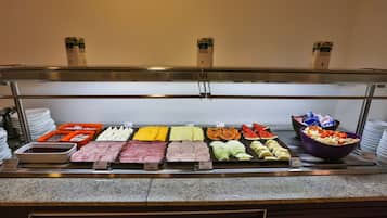 Un bufé con diversos alimentos, incluyendo carnes, quesos, frutas y verduras.