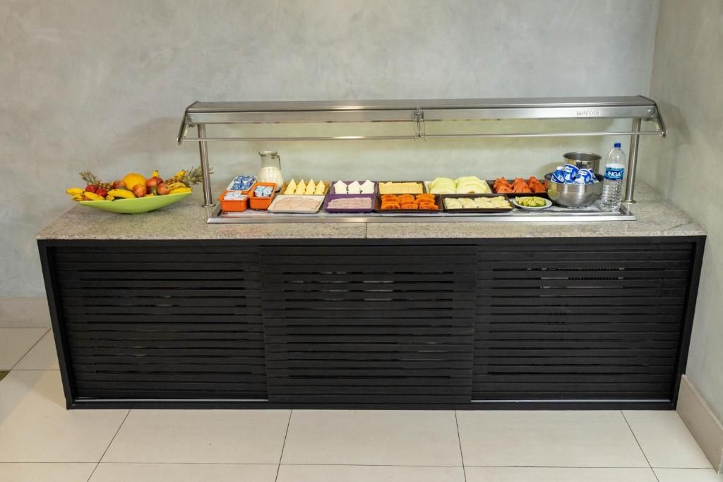 Balcão de buffet com diversos alimentos e um dispensador de água.