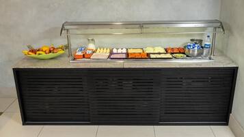 Balcão de buffet com diversos alimentos e um dispensador de água.