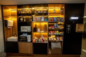 Eine kompakte Minibar mit einer Mikrowelle, verschiedenen Snacks und Getränken.