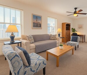 A living room with a sofa, two armchairs, a coffee table, a wooden cabinet, and a ceiling fan. - Stylish Gold Coast 1BR with Vintage Flair (Chicago)