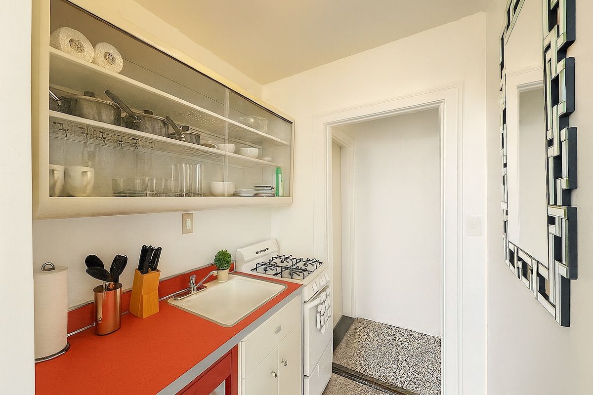 Una cocina compacta con estufa a gas, un lavamanos y una encimera con utensilios.