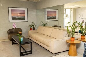 Ein modernes Wohnzimmer mit einem beige-farbenen Sofa, einem schwarzen Couchtisch und Topfpflanzen.