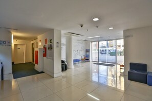 Eine helle, moderne Lobby mit einer Rezeption, einer Sitzecke und freiem Blick nach draußen.