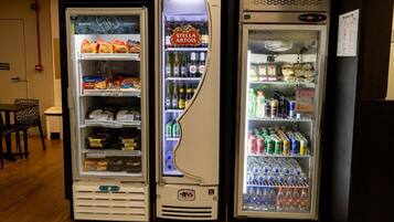 Three beverage vending machines with various drinks and snacks.