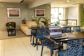 Ein moderner Büroraum mit einem Laptop auf dem Tisch, blauen Stühlen, einem Sofa und zwei gerahmten Bildern an der Wand.