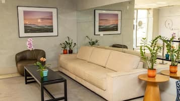 A modern living room with a beige sofa, a black coffee table, and potted plants.