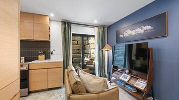Uma sala de estar moderna com um sofá, uma televisão de tela plana e uma estante de livros.