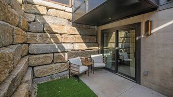 A patio with stone walls, a small lawn, and outdoor seating.