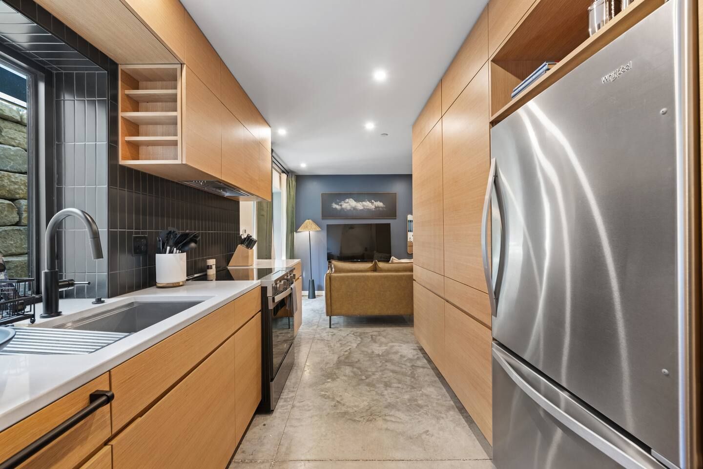 A modern kitchen with wooden cabinetry, a stainless steel refrigerator, and a built-in oven.