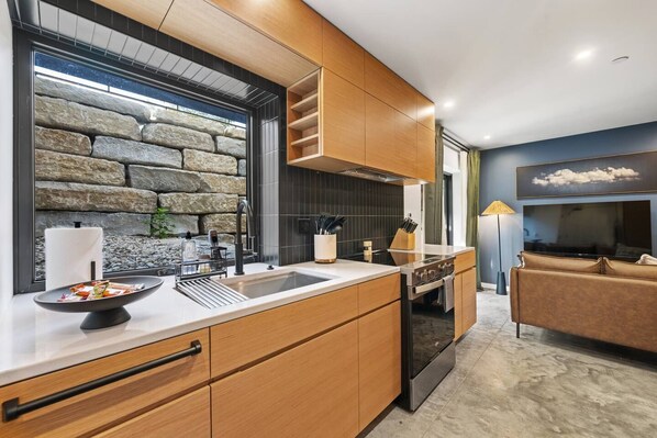 A modern kitchen with a stone wall backsplash, wooden cabinetry, and a built-in oven.