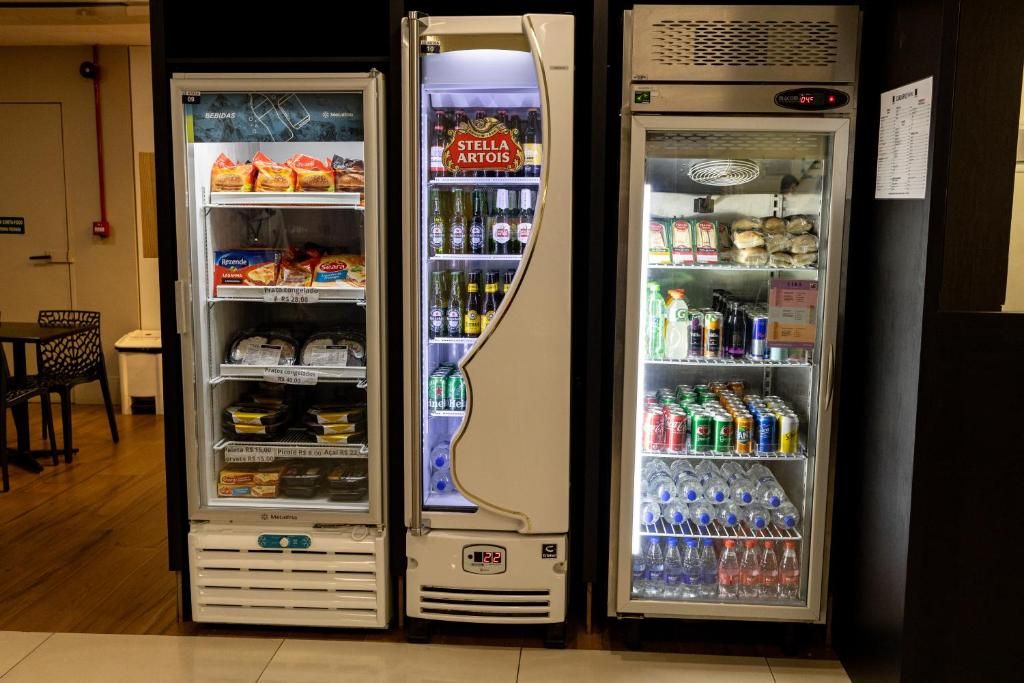 Três máquinas de venda automática com diversas bebidas e lanches.