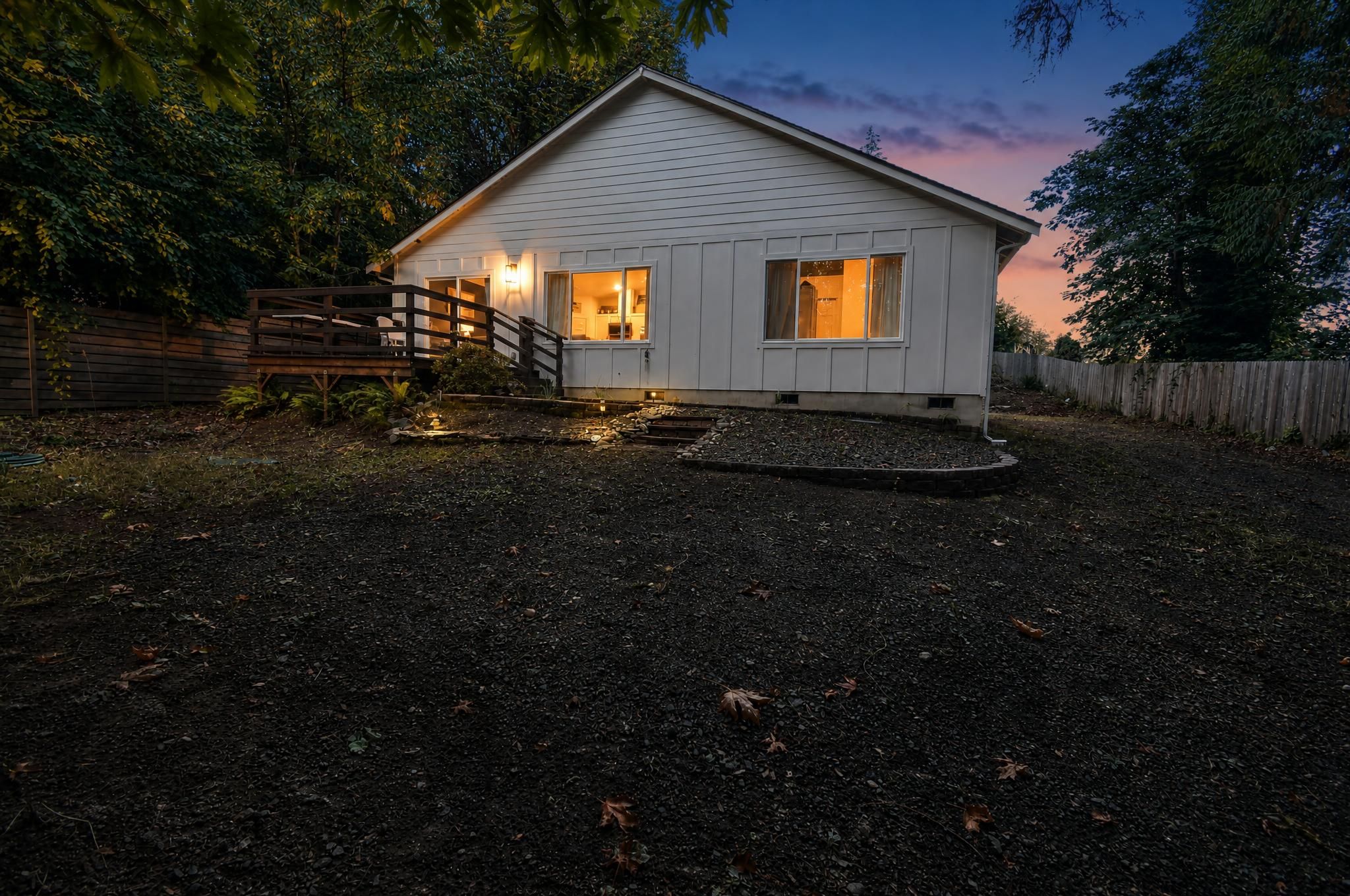 A small, single-story house with a porch and a fenced yard.
