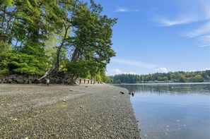 Une plage de galets bordée d’arbres et un lac paisible.