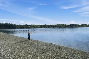 A pebbled shore with a person fishing by the water.