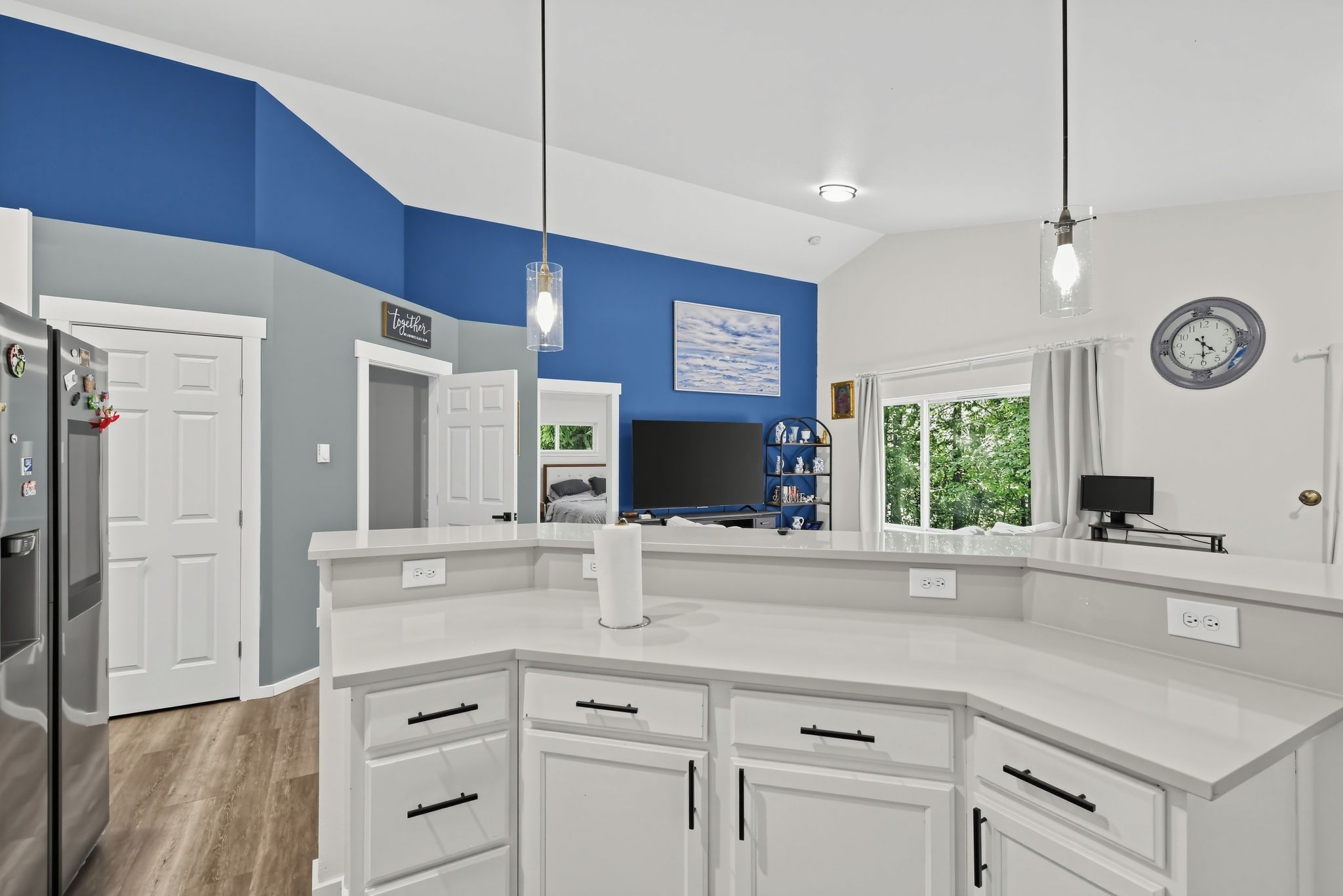 A modern kitchen with white cabinetry, a built-in island, and a large window providing natural light.