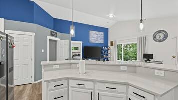 A modern kitchen with white cabinetry, a built-in island, and a large window providing natural light.