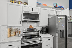 A modern kitchen with white cabinetry, stainless steel appliances, and a coffee maker.