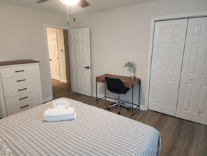 Un dormitorio con una cama, un escritorio, una silla y un armario.