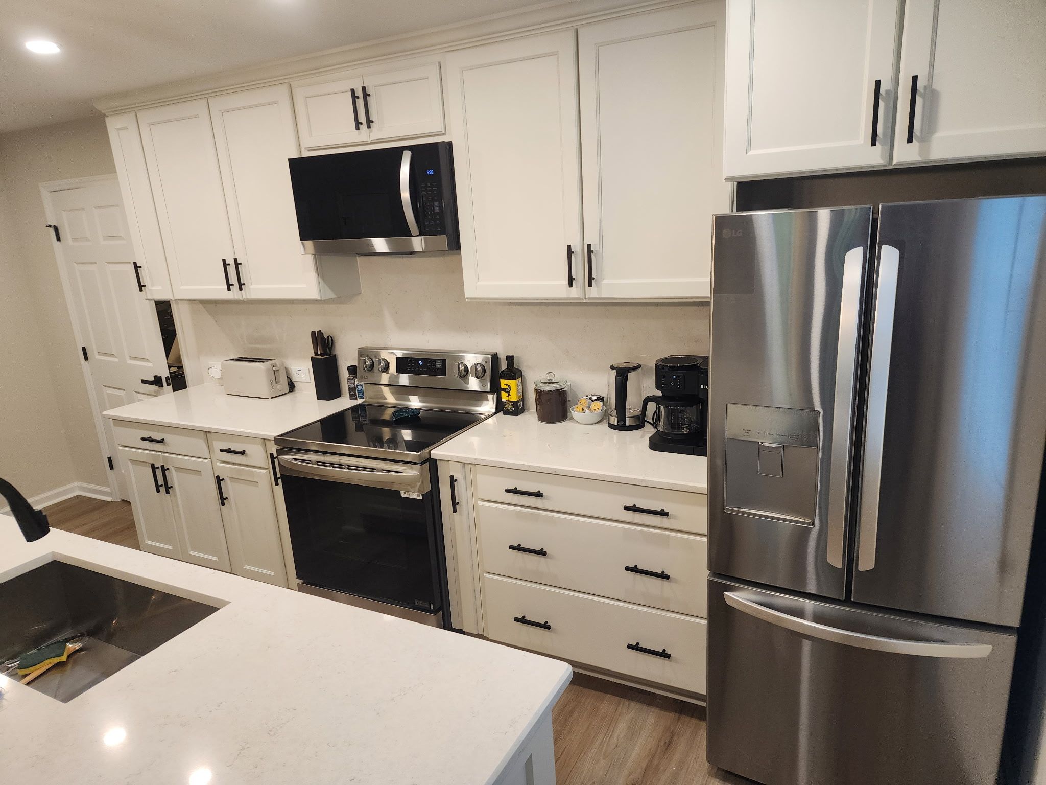 Una cocina moderna con armarios blancos, electrodomésticos de acero inoxidable y un microondas negro.
