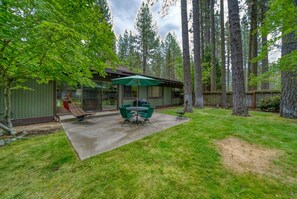 A backyard with a patio, a covered seating area, and a house with a green exterior.