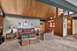 A spacious living room with a high ceiling, a sofa set, a coffee table, and a fireplace.