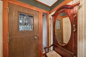 A wooden door with a glass window, a mirror, and a bench.