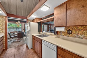 A compact kitchen with wooden cabinets, a dishwasher, and a refrigerator.