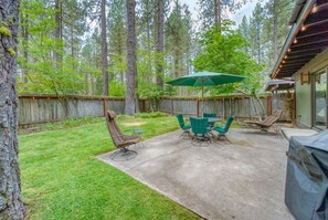 A backyard with a patio, outdoor furniture, and a wooden fence.