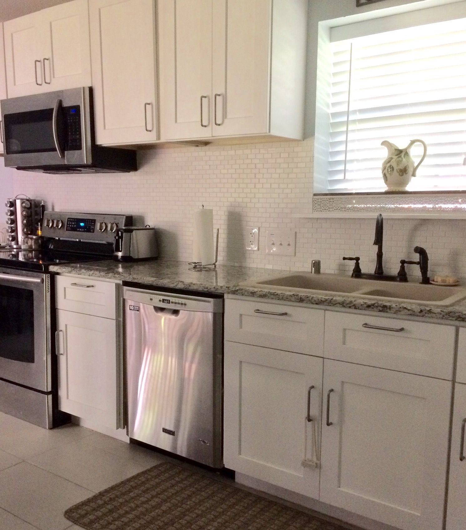 A kitchen with white cabinets, stainless steel appliances, a microwave, a dishwasher, and a sink.