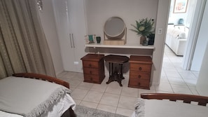 A bedroom with a bed, a dresser, a mirror, and a potted plant. - Salt on South- Beach front views (South Mission Beach)