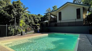A residential property with a swimming pool, a fenced yard, and a house with a balcony.